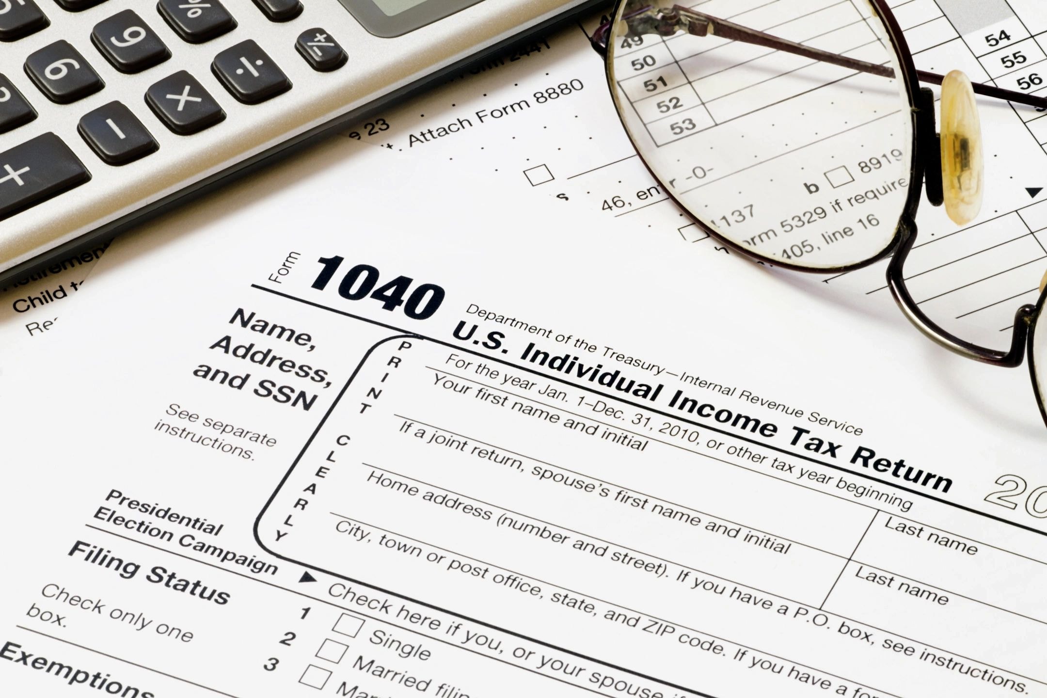 IRS Form 1040 tax return with calculator and glasses